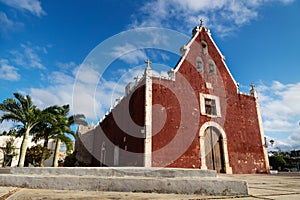 Red colonial church Itzimna in a park with palm trees, Merida, Yucatan, Mexico photo