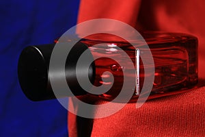 Red color men perfume bottle isolated on red and blue background.