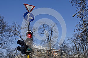 Red color on the traffic light with beautiful blue sky, winter roof and tree branch in background, Sofia