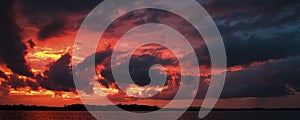 Red colored cumulonimbus cloud, sunset seascape.