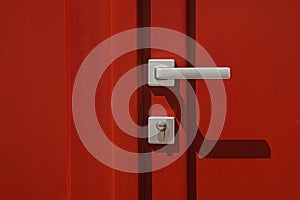 Red colored door with handle and lock close-up