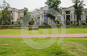 Red-colored path in grassy lawn before fenced villas