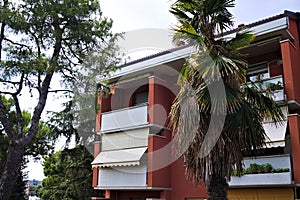 A red colored reinforced concrete residential building with white balconies and awnings Marche, Italy