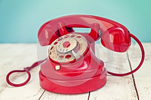 Red colorful vintage telephone over a white wooden table