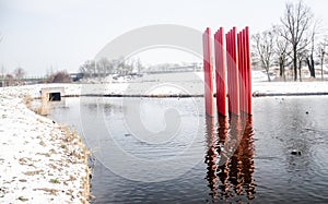 Red colour structure of four set of parallel poles erected in the centre of a lake. Season is Winter with lot of white snow. photo