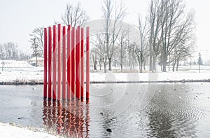 Red colour structure of four set of parallel poles erected in the centre of a lake. Season is Winter with lot of white snow. photo