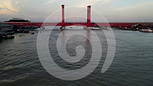Red columns of Ampera bridge over Musi river, low angle drone fly view