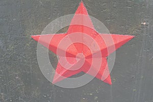Red communist star on cracked khaki wall