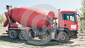 Red concrete mixer vehicle on the construction site