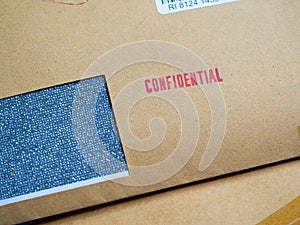 Red `Confidential` word printed on brown vintage envelope in macro. Business confidential concept