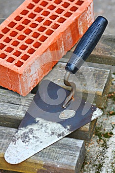 Red construction bricks and trowel on a gray wooden bar