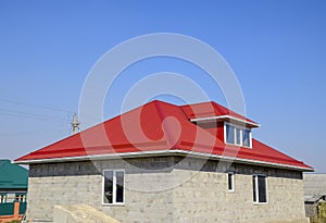 Red corrugated roof. House of cinder block. House with plastic windows and roof of corrugated sheet