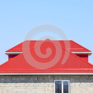 Red corrugated roof. House of cinder block. House with plastic windows and roof of corrugated sheet