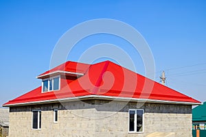 Red corrugated roof. House of cinder block. House with plastic windows and roof of corrugated sheet