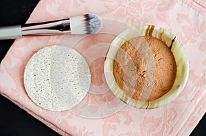 Red cosmetic clay powder in the small onyx bowl and loofah sponge. Homemade beauty mask wrap for skin and hair.