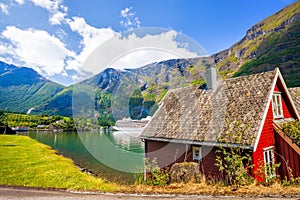 Red cottage against cruise ship in fjord, Flam, Norway