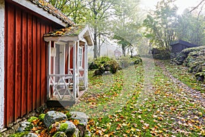 Red cottage with a porch in a rural landscape in the fall