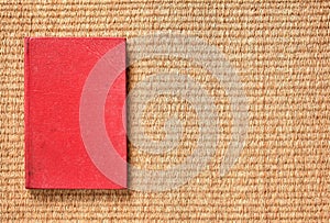 Red cover old notebook on woven natural fiber table mat.