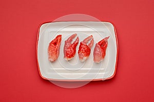 Red crab claws in a white plate on a red background