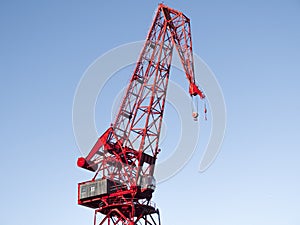 a red crane against a clear blue sky, its structure and machinery detailed, evoking a sense of industrial efficiency