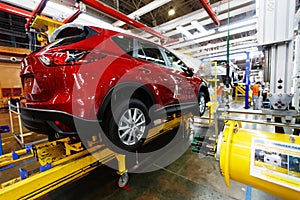 A red crossover is standing on a transport tape at a car factory. Car manufacturing.