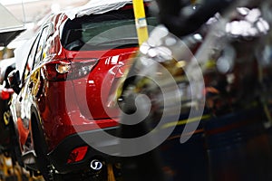 A red crossover is standing on a transport tape at a car factory. Car manufacturing.
