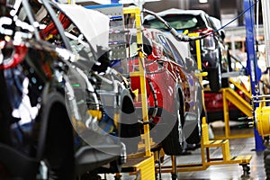 A red crossover is standing on a transport tape at a car factory. Car manufacturing.