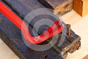 Red crowbar pulling a rusty nail