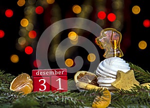 Red cubes calendar date December 31,plate of sweets with marshmallow and caramel as dog background of yellow and red bokeh lights