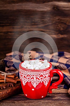 Red cup with cocoa and marshmallows, steam shaped like a heart with cozy plaid