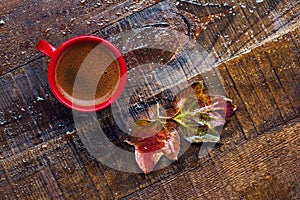 Red cup with  coffee and  autumn leaves on  old  wet wooden table.  Flat lay
