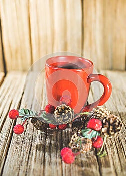 A red cup of coffee with Christmas ornament on the old wooden table top with wood panel background..