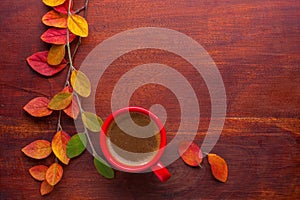 Red cup of coffee and colorful autumn leaves on the wooden table. Top view