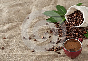 Red cup coffee espresso and coffee beans in burlap sack on a burlap background. Close up, soft focus, copy space for text. Near