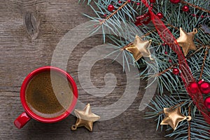 Red cup of coffee and fir branch with Christmas decorations on old wooden background