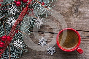 Red cup of coffee, fir branches, red baubles and silver  snowflakes on old wooden  background.  Flat lay. Christmas and New Year h