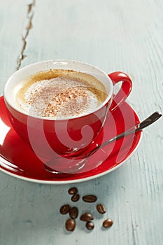Red cup of coffee with spoon on saucer