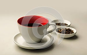 red cup with coffee on a white background close-up and two bowls with coffee beans next to it