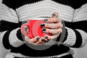 Red cup in hand, black nail polish, black and white background