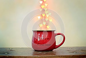 Red cup and heart shaped bokeh over it on white background. Love coffee concept