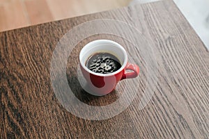 Red cup of hot coffee on wooden table in Coffee shop blur background.