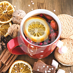 Red cup of hot tea with orange and berries Christmas winter beverage Christmas food concept Wooden background Cinnamone sticks Coo