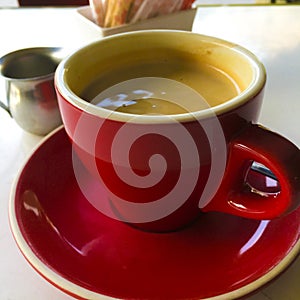 A red cup and saucer of coffee