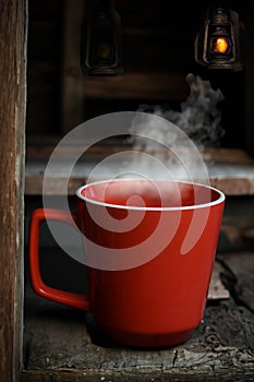 Red cup with steamy mornin coffee in a rustic environment