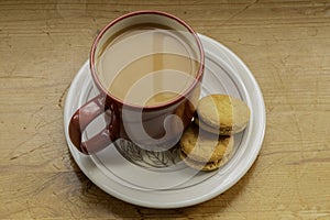 A red cup of tea and two biscuits.