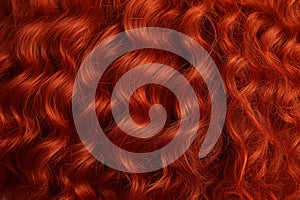 Red curly hair texture close-up, shiny red healthy wavy female hair