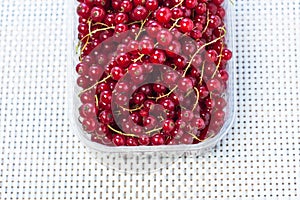 Red currant in a box close-up on a wooden background. Tasty fresh berries, vitamins, vegan, natural, raw food