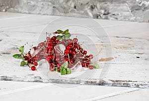 Red currant with ice and green leaves on white wooden background. Still life of food. Cubes of ice with berries.