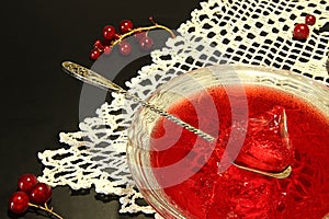 Red currant jelly in glass bowl against black background