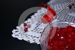 Red currant jelly in glass bowl against black background